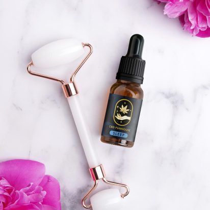 Ulei CBD și rolă facială din cuarț roz pentru o rutină de frumusețe și anti-aging.