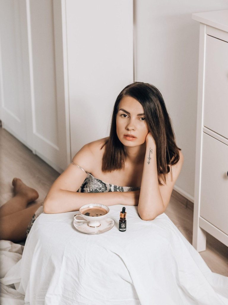 Femeie bucurându-se de un bol cu cereale sănătoase și ulei de cânepă CBD pentru echilibru.