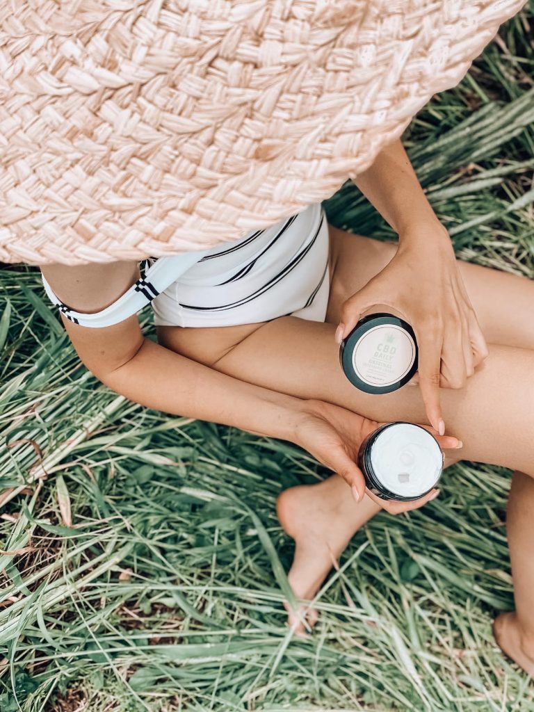 Femeie relaxându-se în iarbă cu setul de cosmetice hidratante CBD Daily.